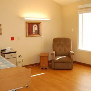 A hospital room featuring a bed, recliner chair, and a bright window.