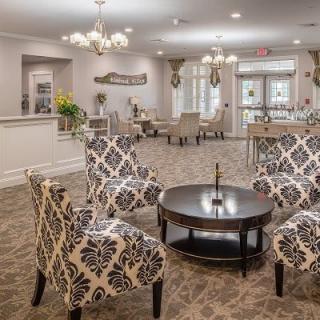 An elegant lobby area featuring patterned chairs, a round table, and a chandelier.