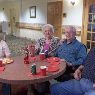 A group of elderly individuals sitting around a table with snacks and drinks.