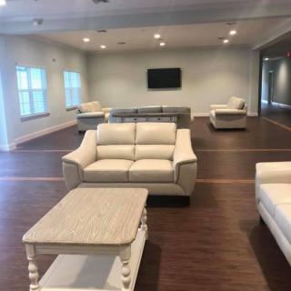 A spacious living room with comfortable sofas and a coffee table, featuring a flat-screen TV on the wall.