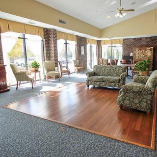 A spacious lobby with ample seating, featuring large windows and a mix of carpet and hardwood flooring.