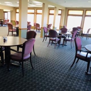 Spacious dining area with multiple tables and chairs, featuring large windows.