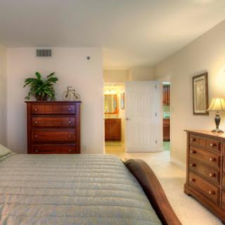 A cozy and well-furnished bedroom showcasing a comfortable bed, decorative furniture, and a touch of greenery.