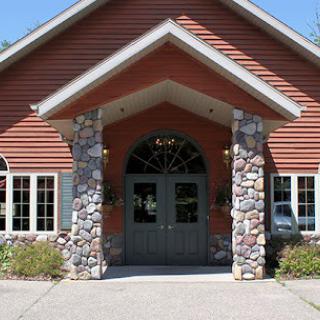 A building with stone pillars and wood siding at the entrance.