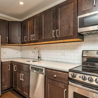 A modern kitchen with dark wood cabinets and stainless steel appliances.