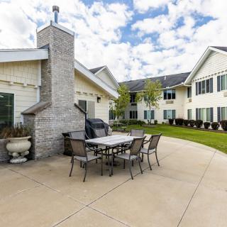 A spacious patio area with a table, chairs, and a chimney next to a residential building.