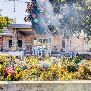 A sunny day in a vibrant garden with outdoor seating and an American flag, showcasing the beauty of nature.
