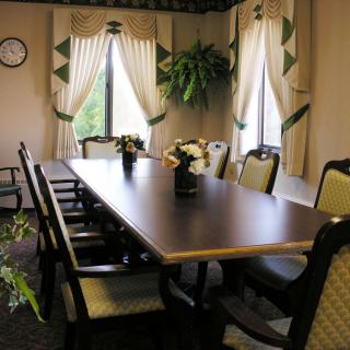 A well-appointed conference room with a long meeting table and several chairs, complete with decorative curtains and an indoor plant.