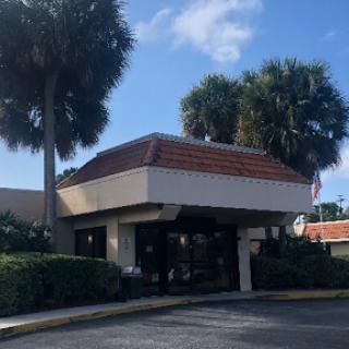 A commercial building surrounded by palm trees under a clear blue sky.