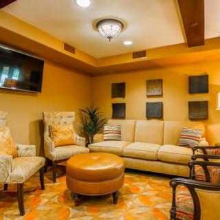 A cozy living room with a comfortable sofa, armchairs, and an ottoman, complemented by warm lighting and decorative wall art.