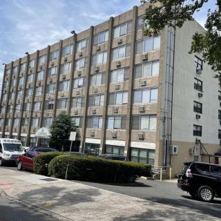 A multi-story residential apartment building with parked cars in the foreground.