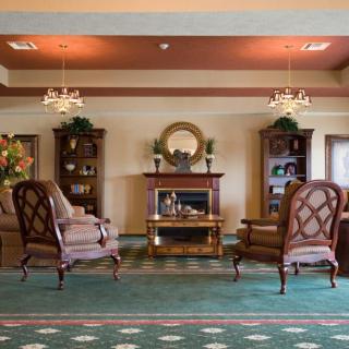 An elegant lobby with armchairs, a fireplace, and decorative bookshelves.
