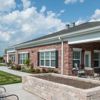 A modern brick residential building with a patio and outdoor seating on a sunny day.
