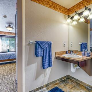 A cozy bathroom interior featuring a sink with a mirror, blue towel, decorative lighting, and a glimpse of a bedroom in the background.