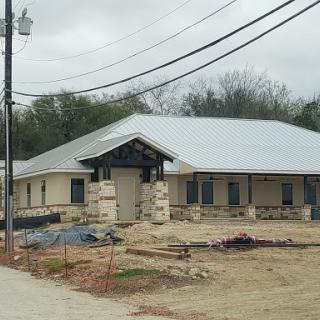 A new building under construction, showcasing modern architectural design amidst a cloudy sky.