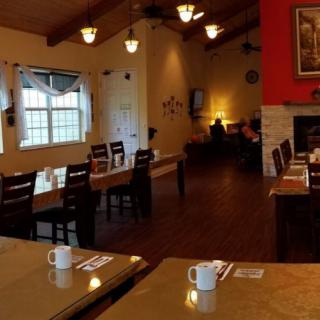 A cozy restaurant interior with neatly arranged tables and chairs, softly lit by warm lighting.