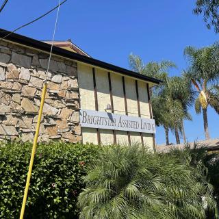 A building with a stone facade and prominent sign, surrounded by palm trees on a sunny day.