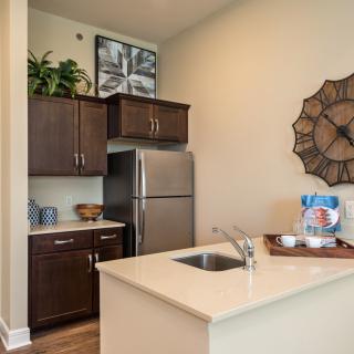 A modern kitchen with dark wood cabinets, stainless steel fridge, and a sleek countertop.