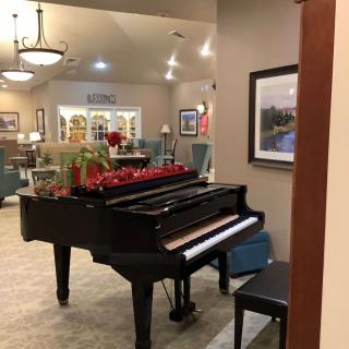 A beautifully decorated living room featuring a grand piano and artwork on the walls.