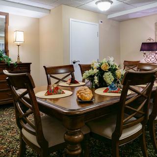 A warmly lit dining room featuring a wooden table set with decorative placemats and a floral centerpiece.