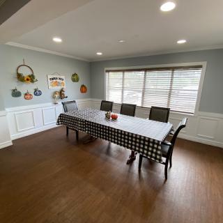 A spacious and modern dining room featuring a large table and stylish chairs, illuminated by natural light from the windows.