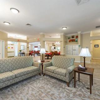 A spacious living room featuring comfortable sofas, carpet flooring, and ambient lighting.