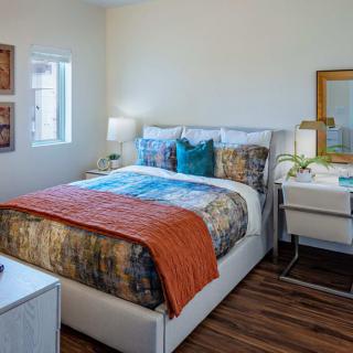 A cozy bedroom with a colorful bedspread, bedside tables, and a desk with a mirror.