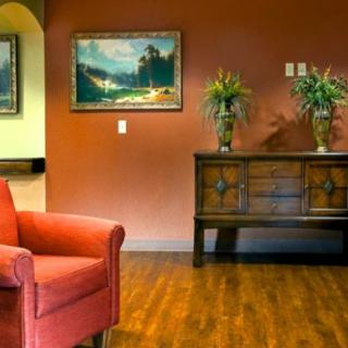 A cozy living room with a red chair, wooden console table, and artwork on the wall.
