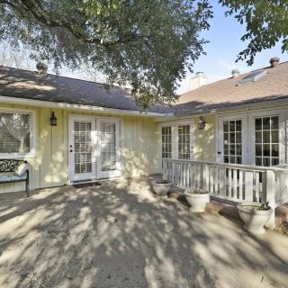 A house exterior with a patio and trees casting shadows.