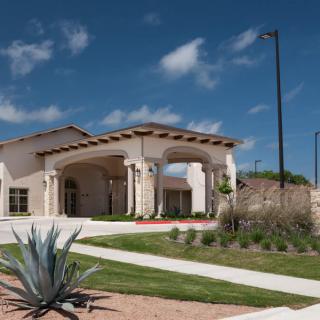 A modern residential building with landscaped surroundings under a clear blue sky.
