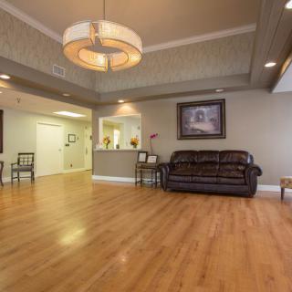A cozy living room with a sofa, wood flooring, and a large lighting fixture.