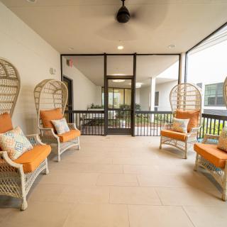 A cozy screened patio with comfortable seating and a ceiling fan.