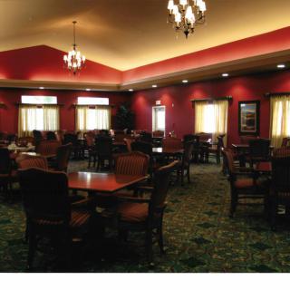 A spacious dining room with elegant chandeliers, red walls, and neatly arranged tables and chairs.
