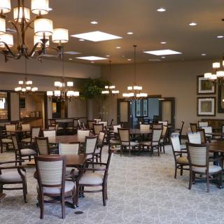 A spacious dining area with neatly arranged tables and chairs, featuring elegant lighting fixtures.
