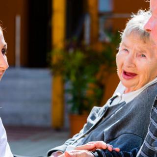 A healthcare worker interacting with an elderly person outside.