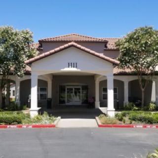 A well-maintained building entrance with surrounding trees and clear blue sky.