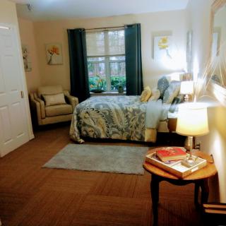 Cozy bedroom with a stylish bed, armchair, and warm lighting.
