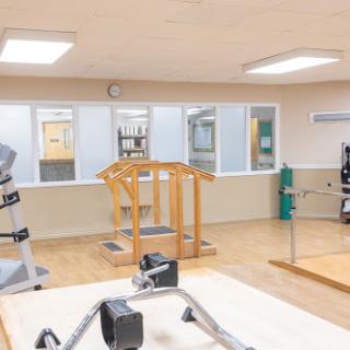 A bright and spacious gym area equipped with various exercise machines, ideal for physical therapy and rehabilitation.