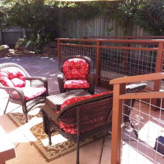 A sunny patio with comfortable outdoor furniture and red cushions.