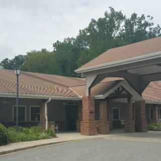 A building with a covered entrance and surrounded by trees.