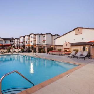 A hotel with an outdoor swimming pool and lounge chairs, perfect for relaxation.
