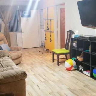 A cozy living room with a sofa, television, and wooden flooring.