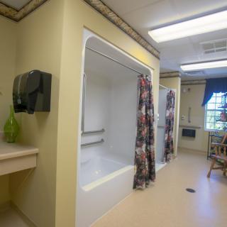 An accessible bathroom with a bathtub and handrails, featuring a curtain for privacy.