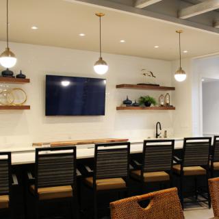 A modern kitchen with bar seating and decorative shelves.