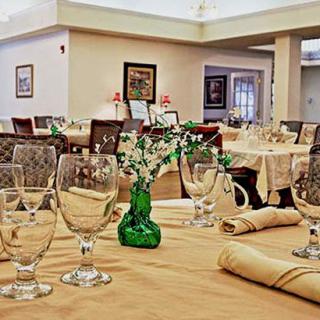 An elegantly set dining table in a restaurant with neatly arranged glasses, napkins, and a small vase centerpiece.