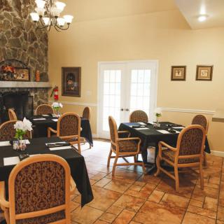 A cozy dining room with elegantly set tables and a stone fireplace.