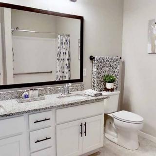 A modern bathroom with a large mirror, sink, and neatly arranged towels.