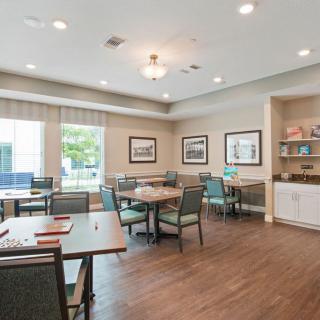 A well-lit dining area with tables and chairs, featuring a hardwood floor and decor on the walls.