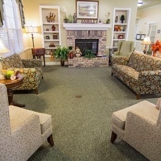 A cozy living room with sofas and chairs arranged around a fireplace.