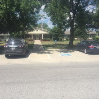 A peaceful residential area featuring parked cars and a house surrounded by trees.